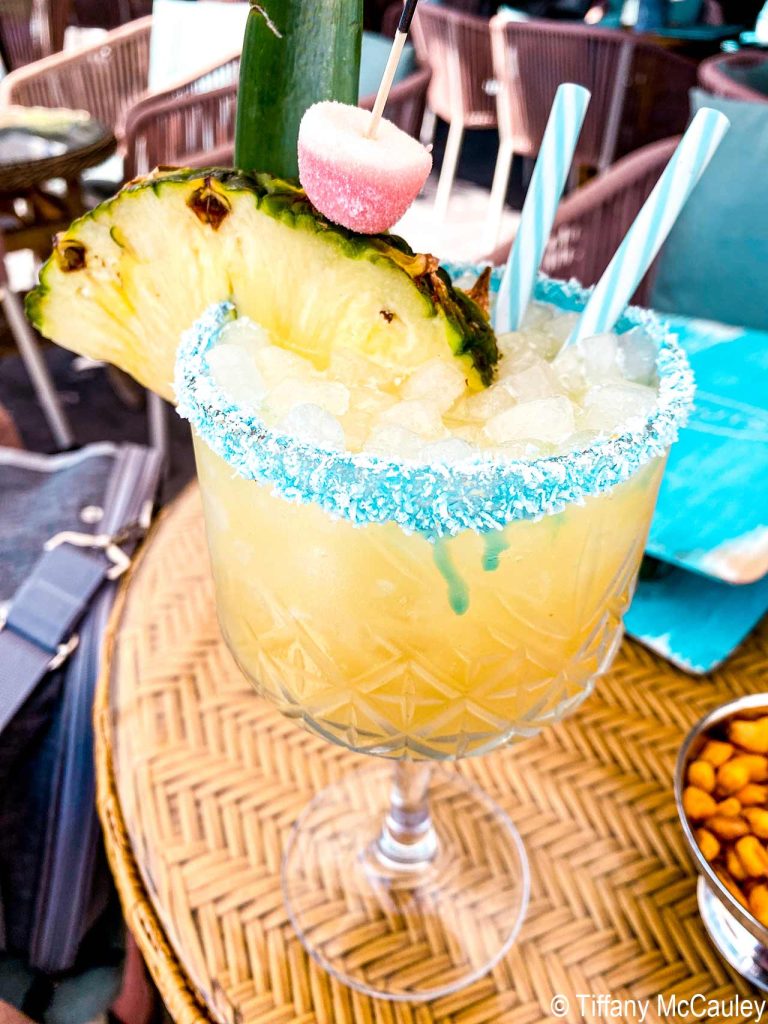 A fruity pineapple drink with straws and a large slice of pineapple.